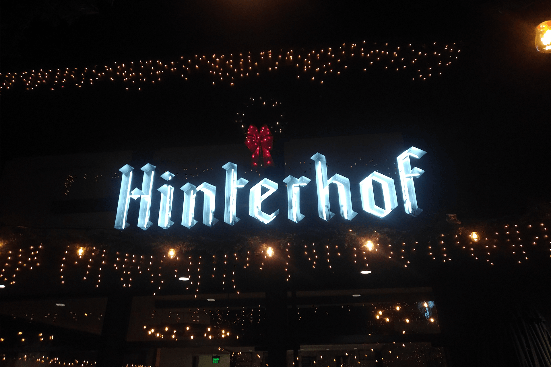 hinterhof sign infront of hinterhof vegan restaurant and beer garden with white lights surrounding it and a wreath above it